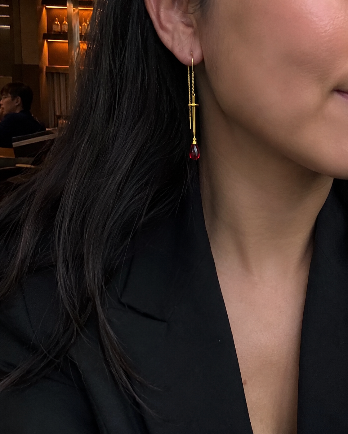 Close-up of a woman wearing a 18k gold sword threader earring with natural ruby | the sovereign by eliza
