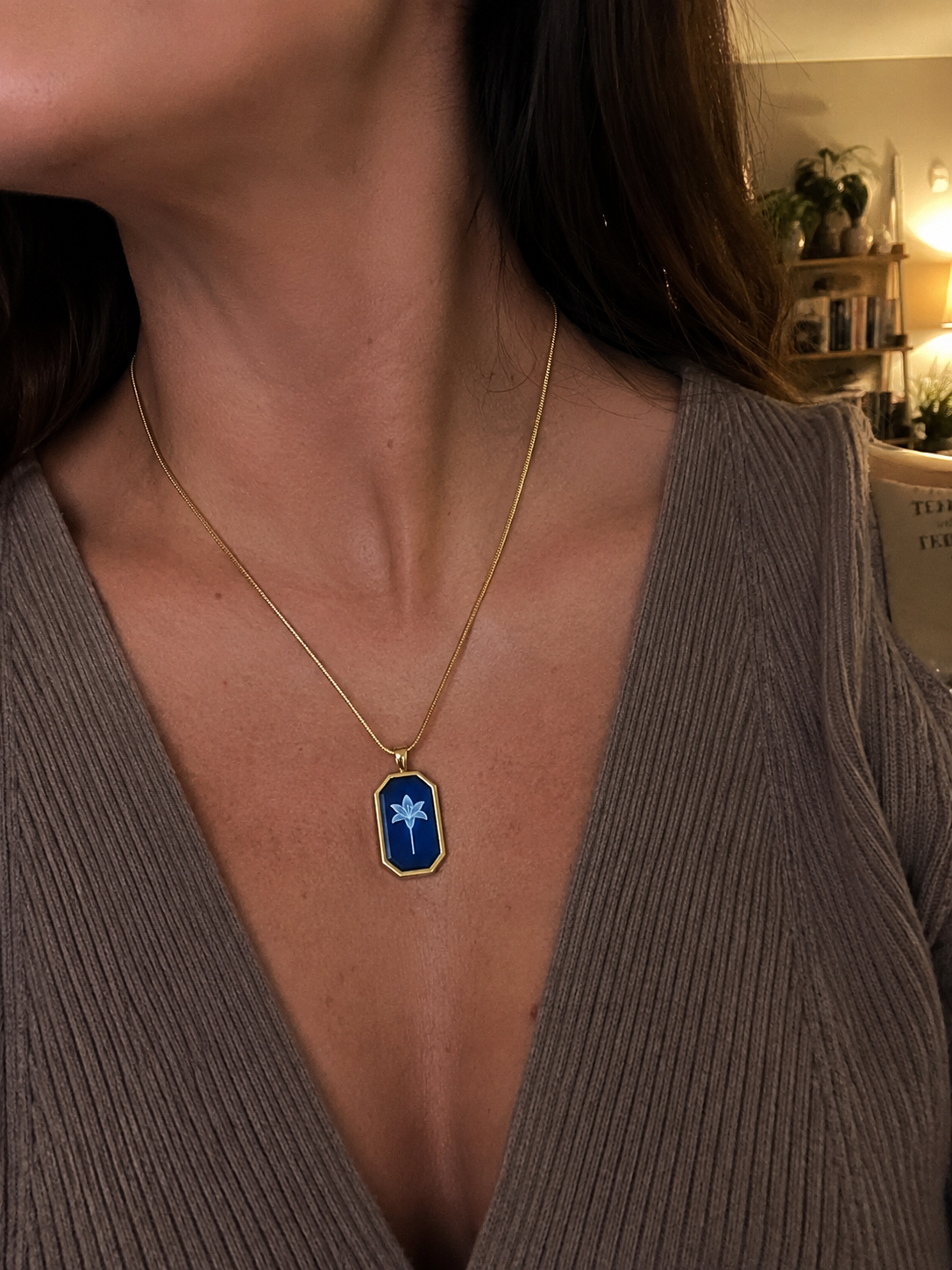 Close-up of a person wearing a gold necklace with a blue pendant.